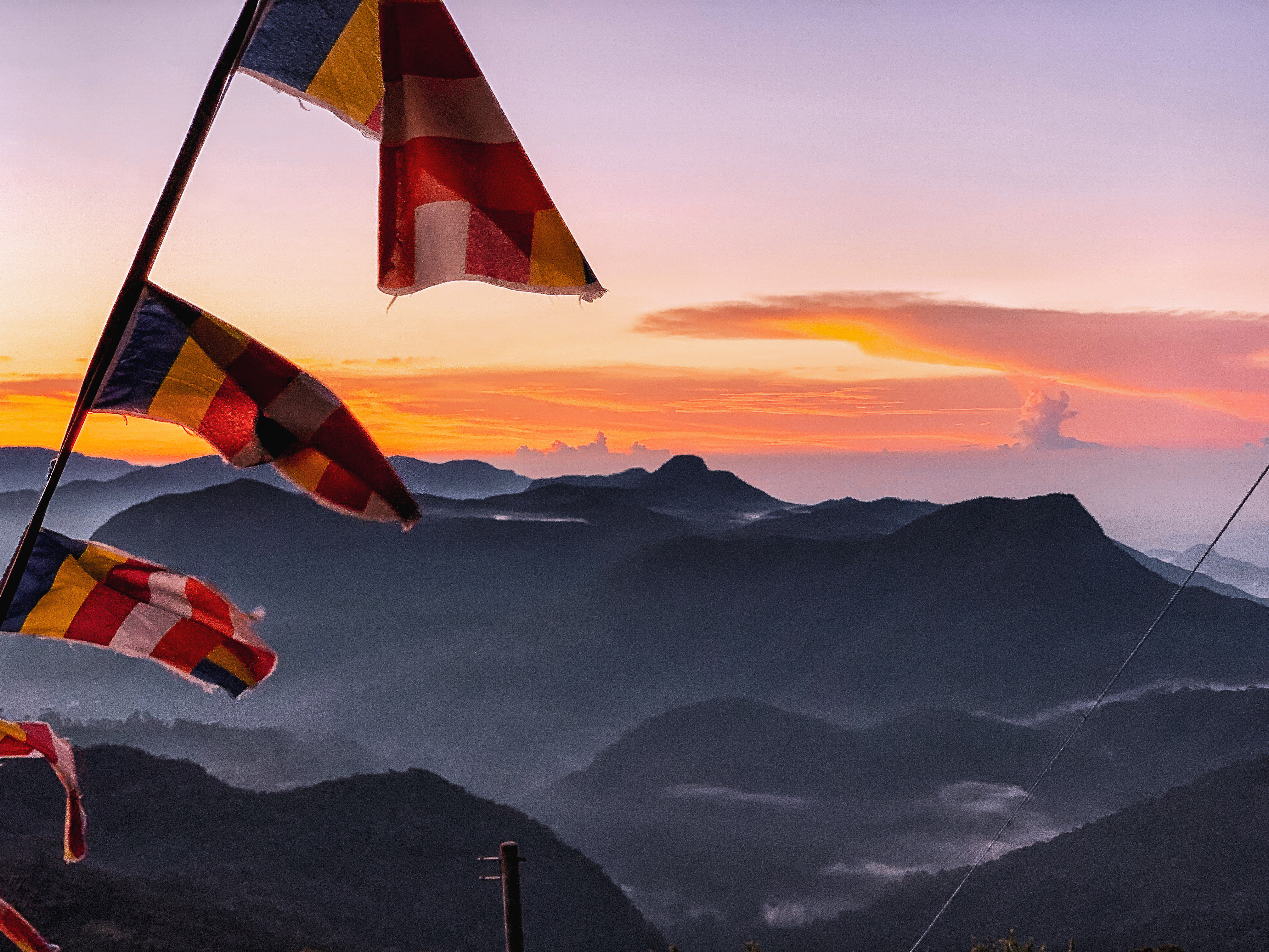 Sunrise from the summit of Sri Pada (Adam's Peak) with golden light over misty mountains in Sri Lanka