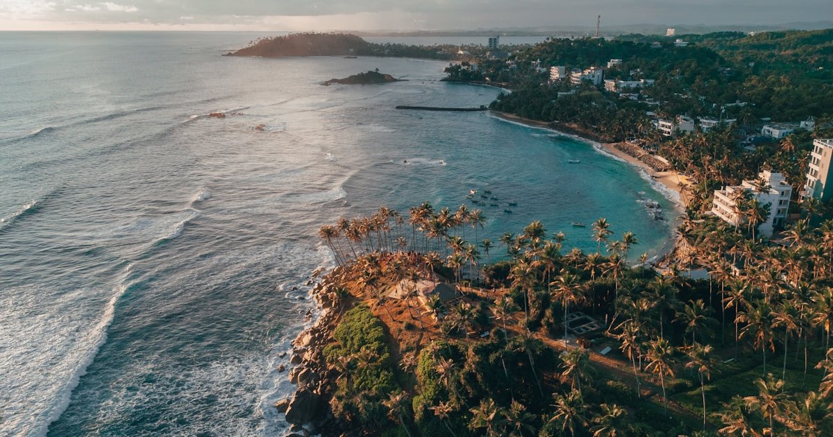 Aerial view of Mirissa beach with its curved coastline and palm trees
