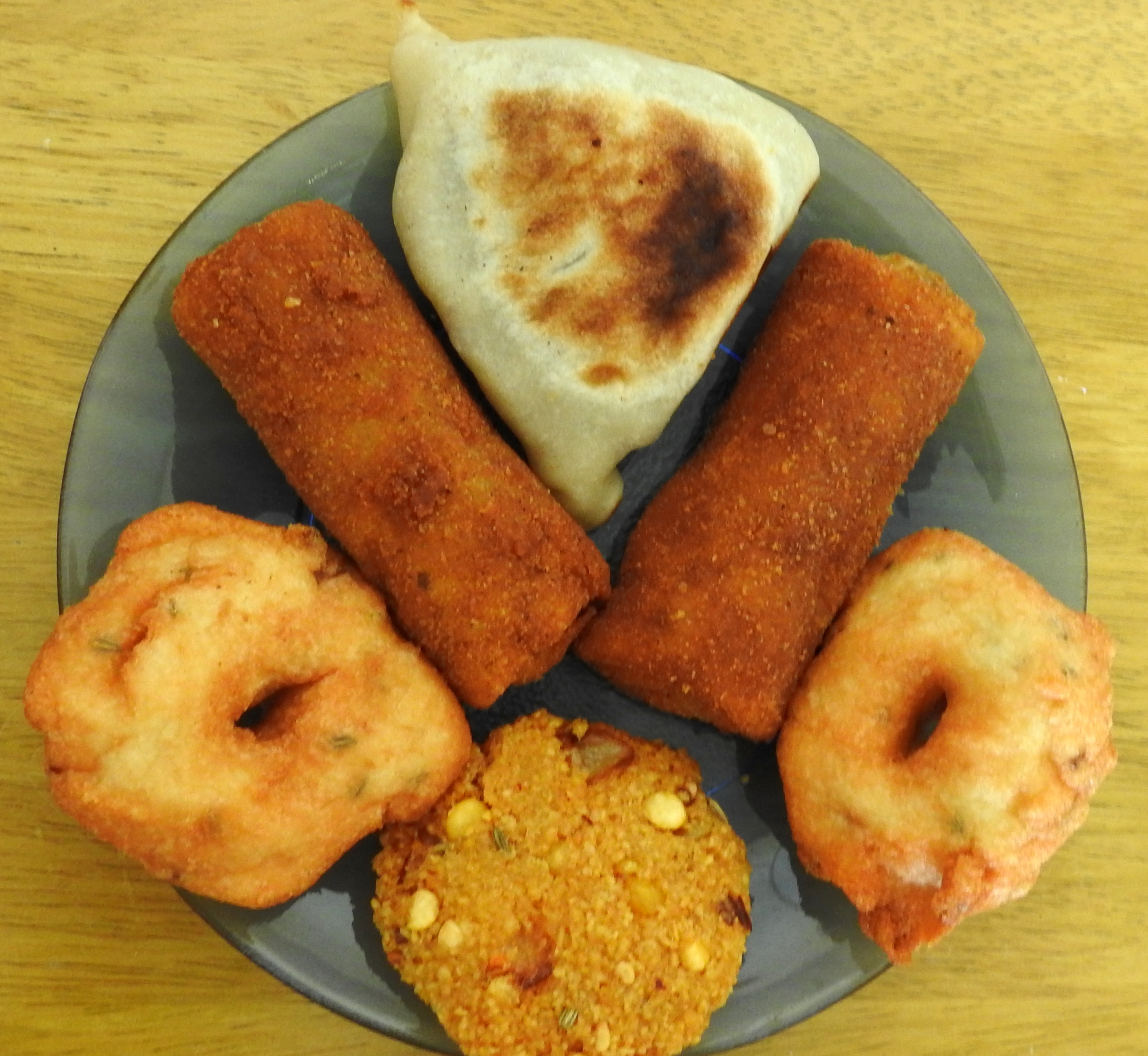 A plate of traditional Sri Lankan pastries and fried snacks on a table